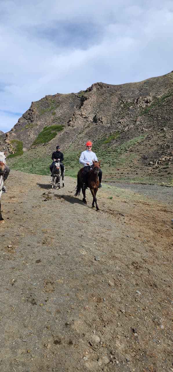 Riders on horseback crossing a mountain trail in the Mongolian countryside